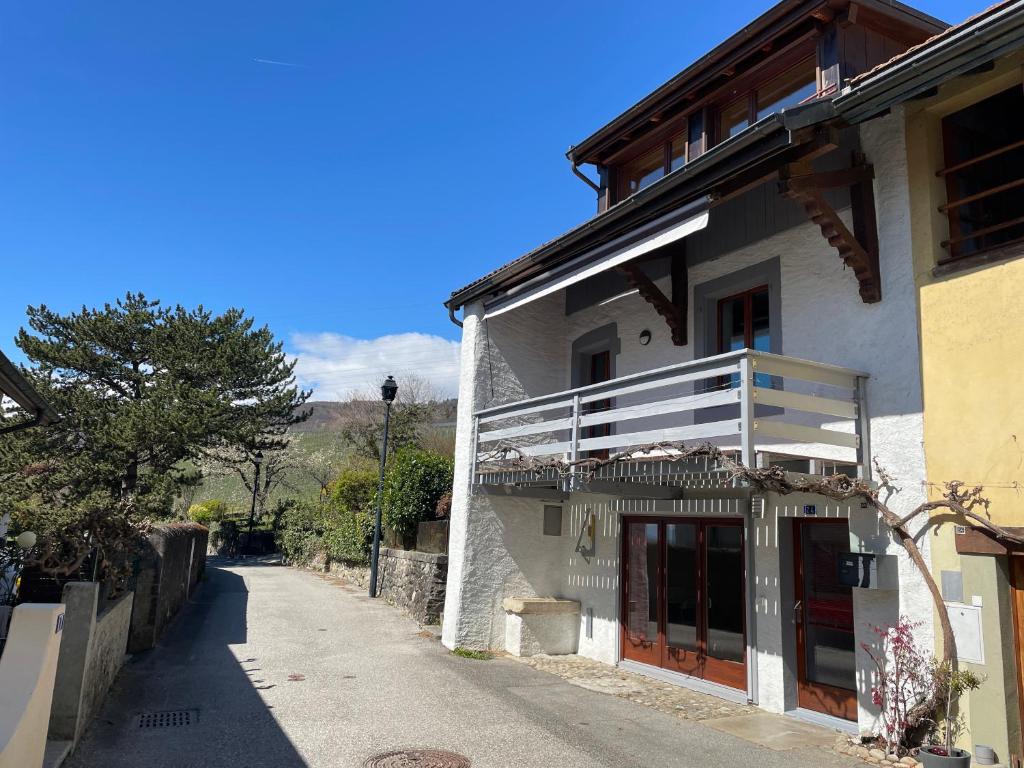 a white building with a balcony on a street at La cameretta in Mont-sur-Rolle