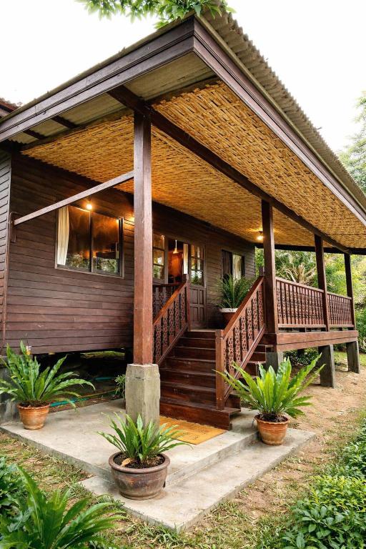a house with a large wooden porch with potted plants at Hidden Home Samui in Koh Samui