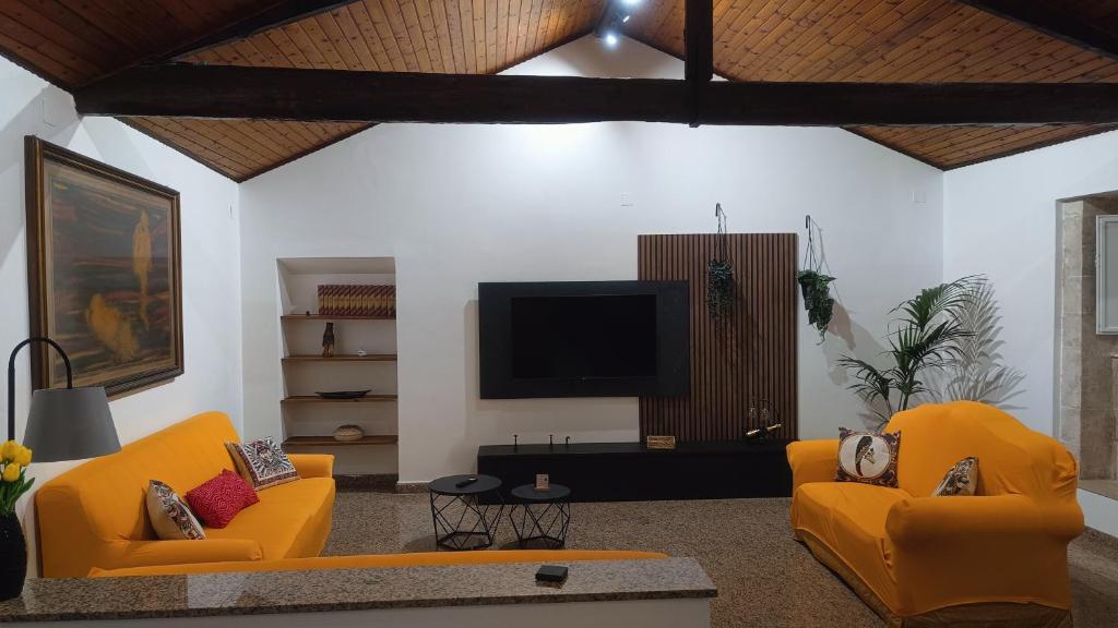 a living room with two orange chairs and a flat screen tv at Archimede29 in Syracuse