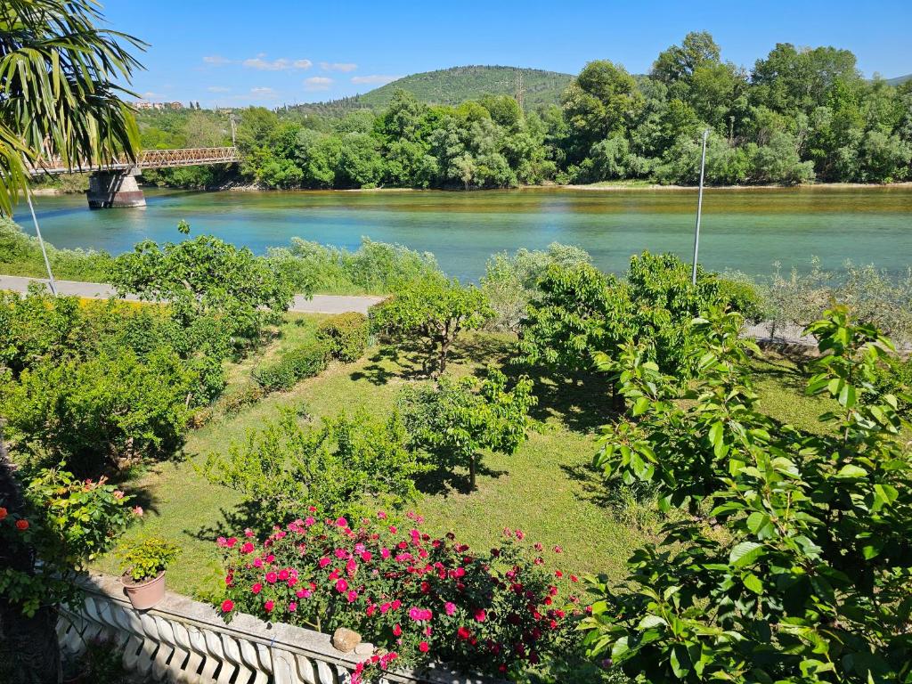 a garden with flowers and a river with a bridge at Kiki - Emerald River Suite with Private Gardens in Čapljina