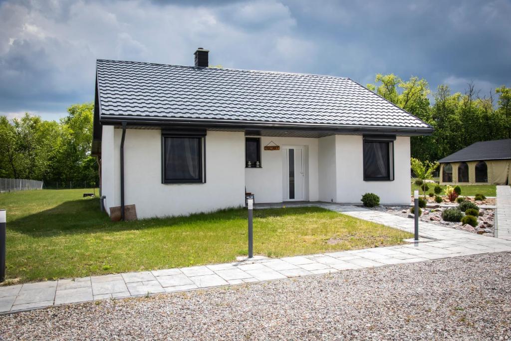 a white house with black windows and a driveway at Domki letniskowe Malina 1 in Gawrony