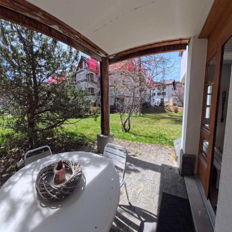 a table and chairs on a patio with a view of a yard at Wellness apartment with pool and terrace in Lenzerheide