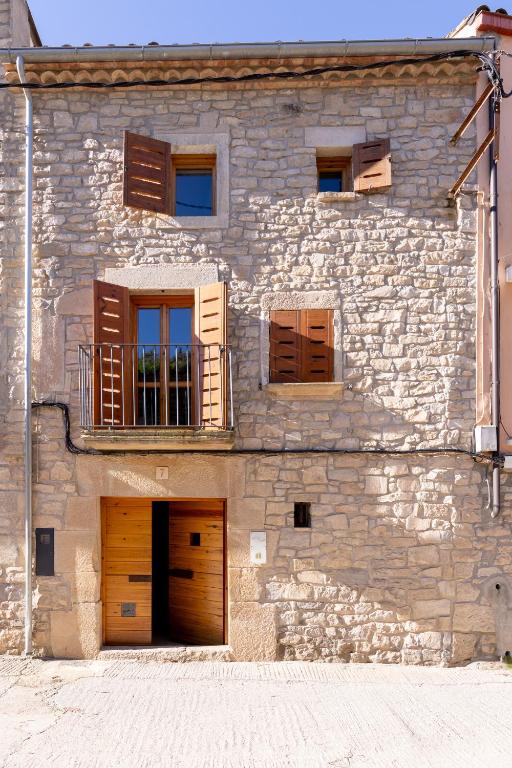 a stone building with two doors and a balcony at Ca la Bepa in Rocafort de Vallbona