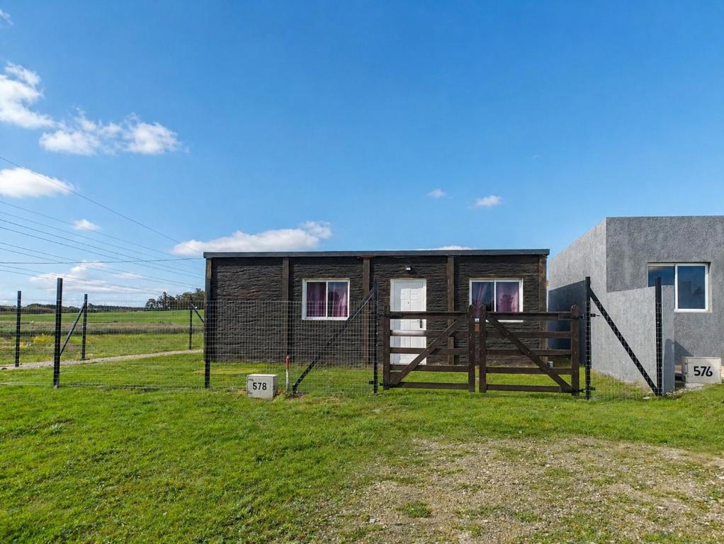 a small house in a field next to a building at Refugio del Horizonte Colonia in Colonia del Sacramento