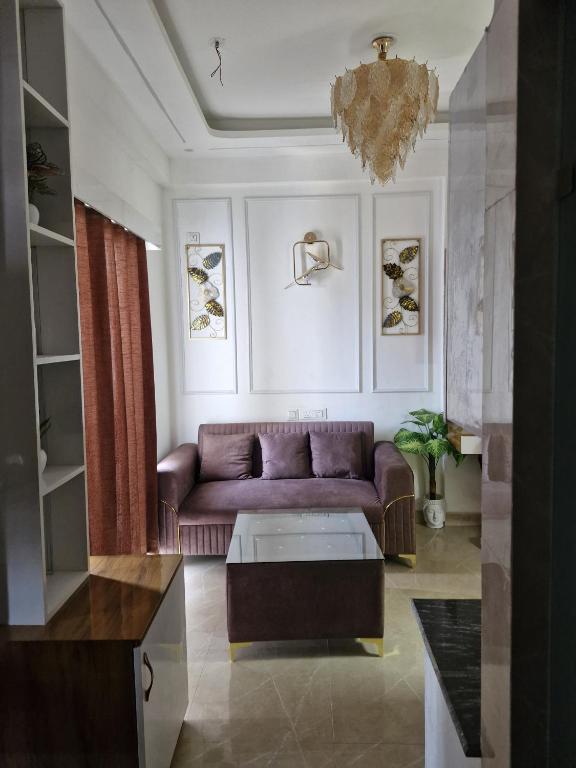 a living room with a purple couch and a chandelier at The Happy Nook Stays in Winsten Park Knowledge Park V in Noida
