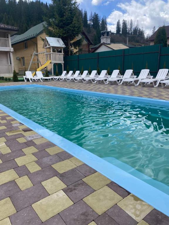 ein Swimmingpool mit Liegestühlen und Stühlen in einem Haus in der Unterkunft Pogar White in Slawske