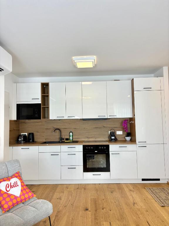 a kitchen with white cabinets and a couch in a room at Beach SUN and FUN in Podersdorf am See