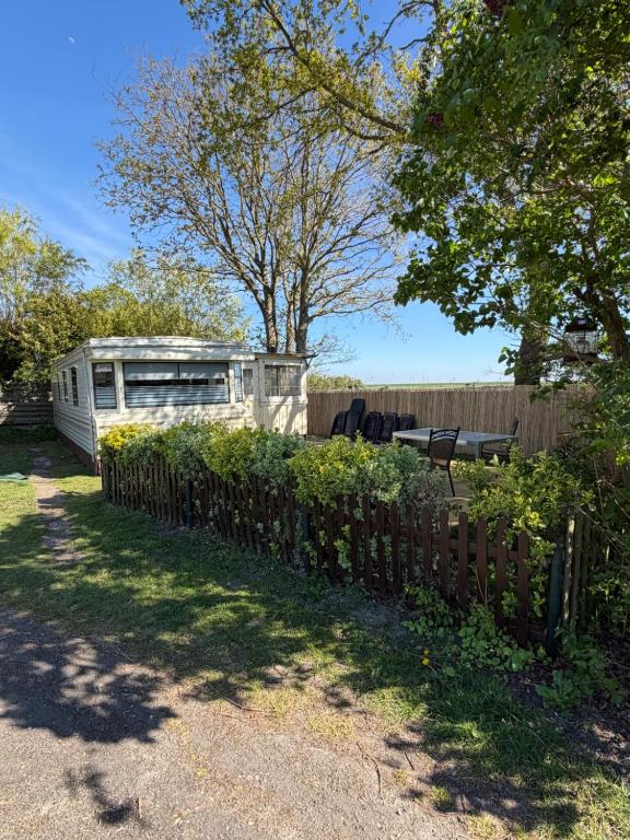 a trailer in a yard next to a fence at Stacaravan Het Zicht in Scherpenisse