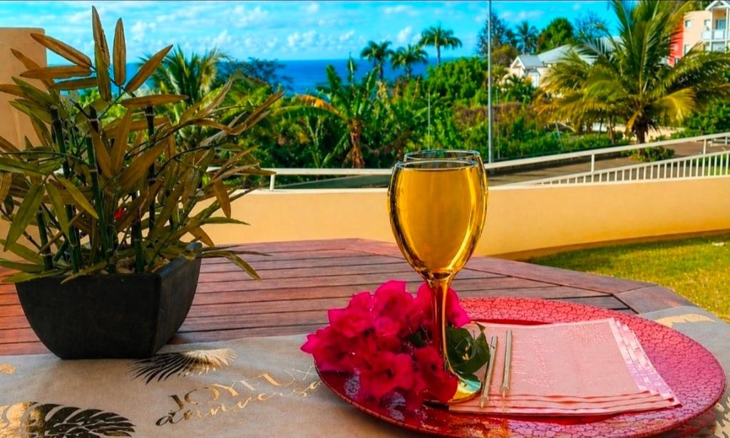 a table with a glass of wine and a plate of flowers at Studio vue sur la mer, piscine - L'Oasis de Tartane in La Trinité