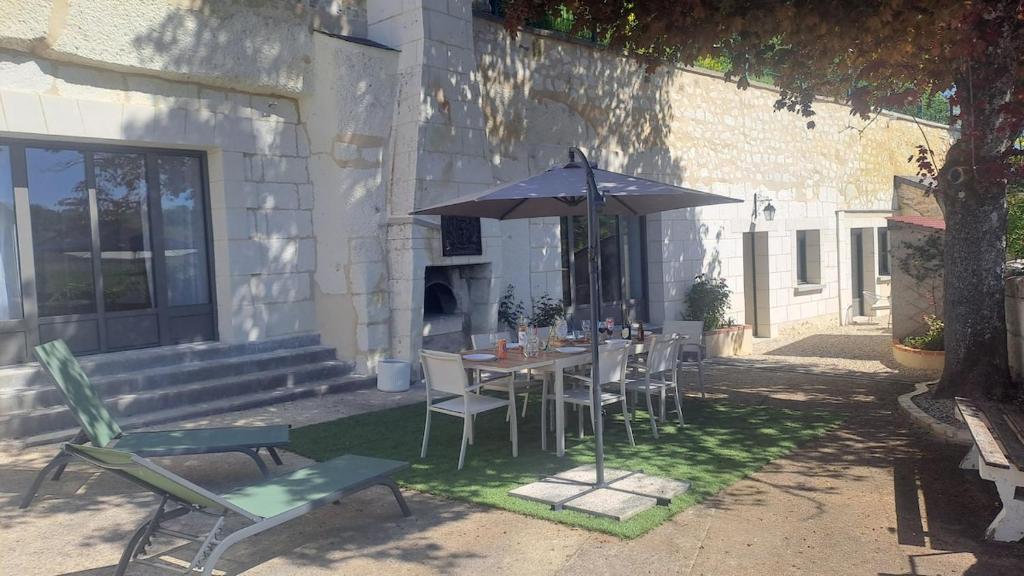 a table and chairs with an umbrella in front of a building at Le logis troglodyte in Loches