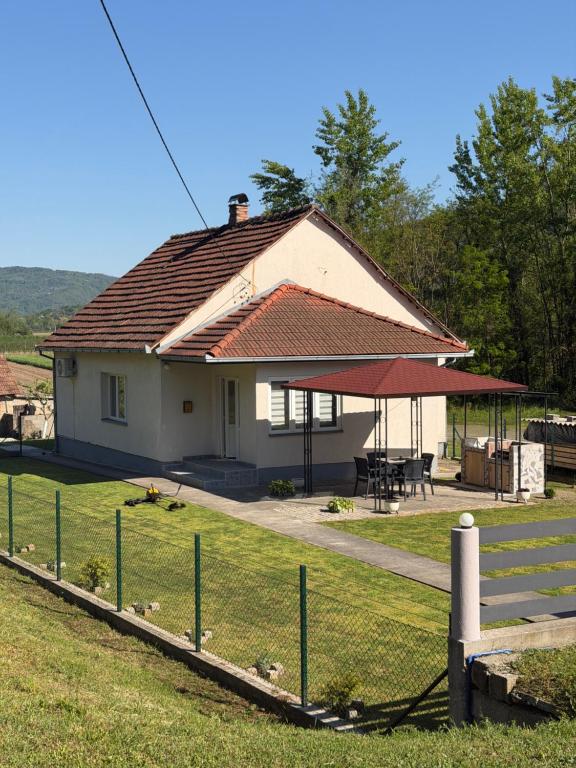 a white house with a roof and a picnic table at Vikendica Lazic in Crnča