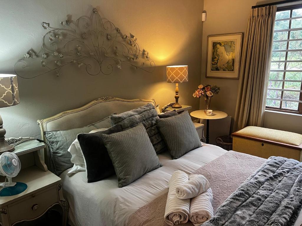 a bedroom with a large bed with pillows at Greyton Cottage in Greyton