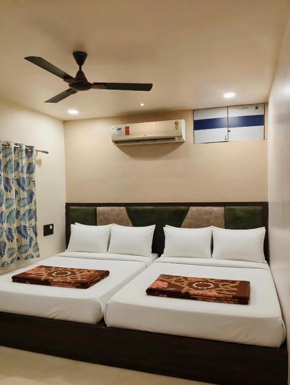 a bedroom with two beds and a ceiling fan at Shreeji guest house Mount Abu in Mount Ābu