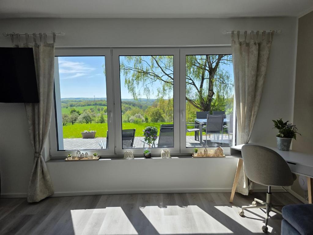 a living room with a large window with a view of a yard at Panorama trifft Gemütlichkeit FeWo Panoramablick in Nümbrecht