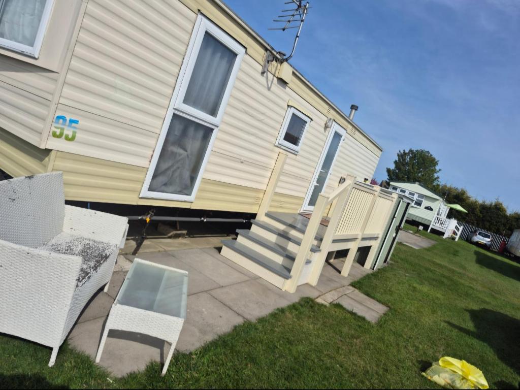 a house with a set of stairs and chairs in the yard at Jams Caravan in Skegness