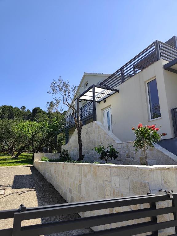 a house with a stone retaining wall and a staircase at Apartman Lara in Pašman