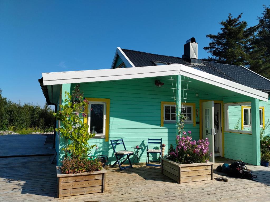 a green house with a patio and flowers at Høgberget Loft with 3 bedrooms and private bathroom in Skotten