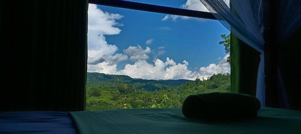a bedroom window with a view of a mountain at Rainforest Hide View in Deniyaya