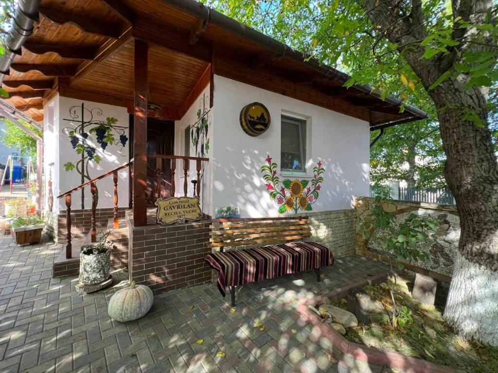 a house with a bench and a tree at Pensiunea Beciul Vechi in Mileştii Mici