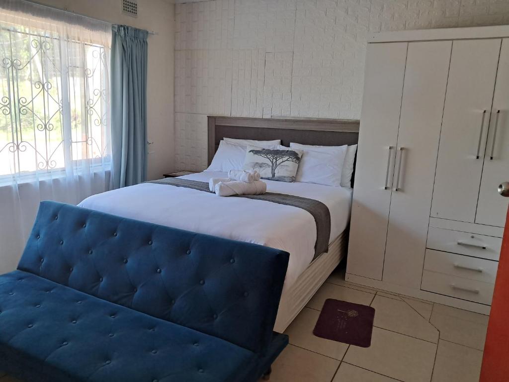 a bedroom with a large bed with a blue ottoman at 25 Jacaranda Lodge & Backpackers in Pinetown