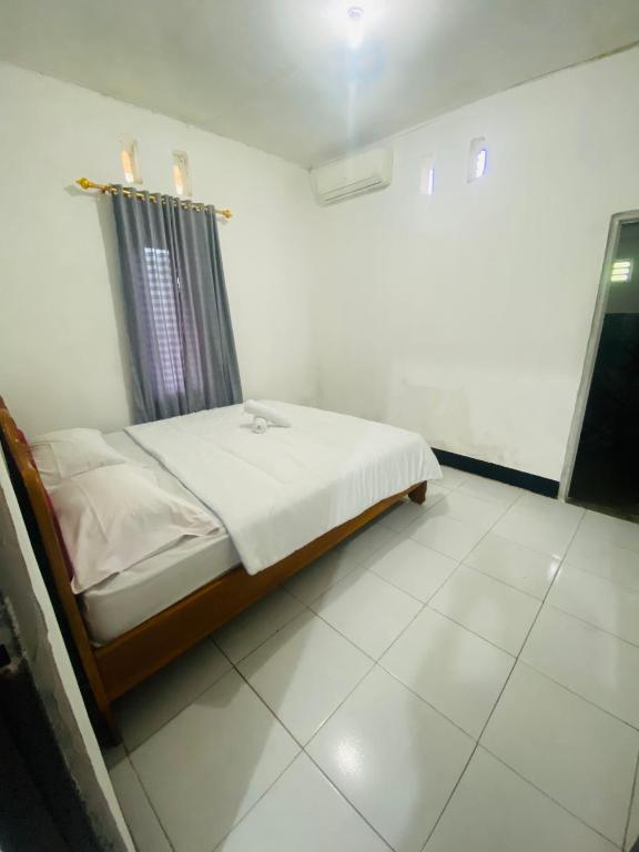 a bedroom with a bed in a white room at Tiba Meka Homestay in Komodo Labuan Bajo Airport