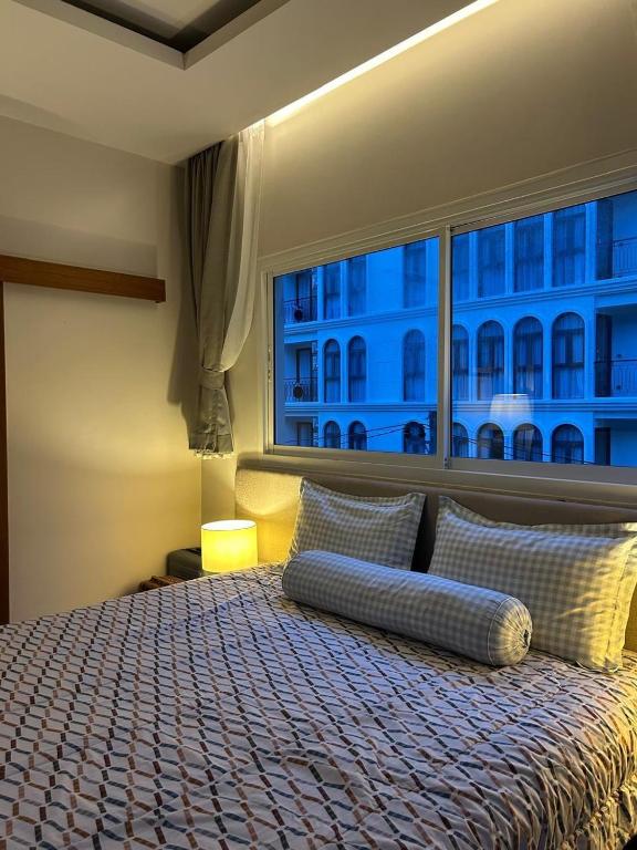 a bedroom with a large bed with a large window at Blue Sky Condo by Palmetto Karon in Ka Rorn