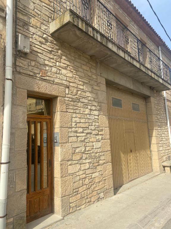 a brick building with a wooden door and a balcony at Cal Pelat Guimerà in Guimerá