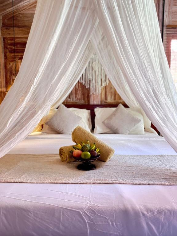 a bed with a canopy with a bowl of fruit on it at Joglo Ulu Home in Uluwatu
