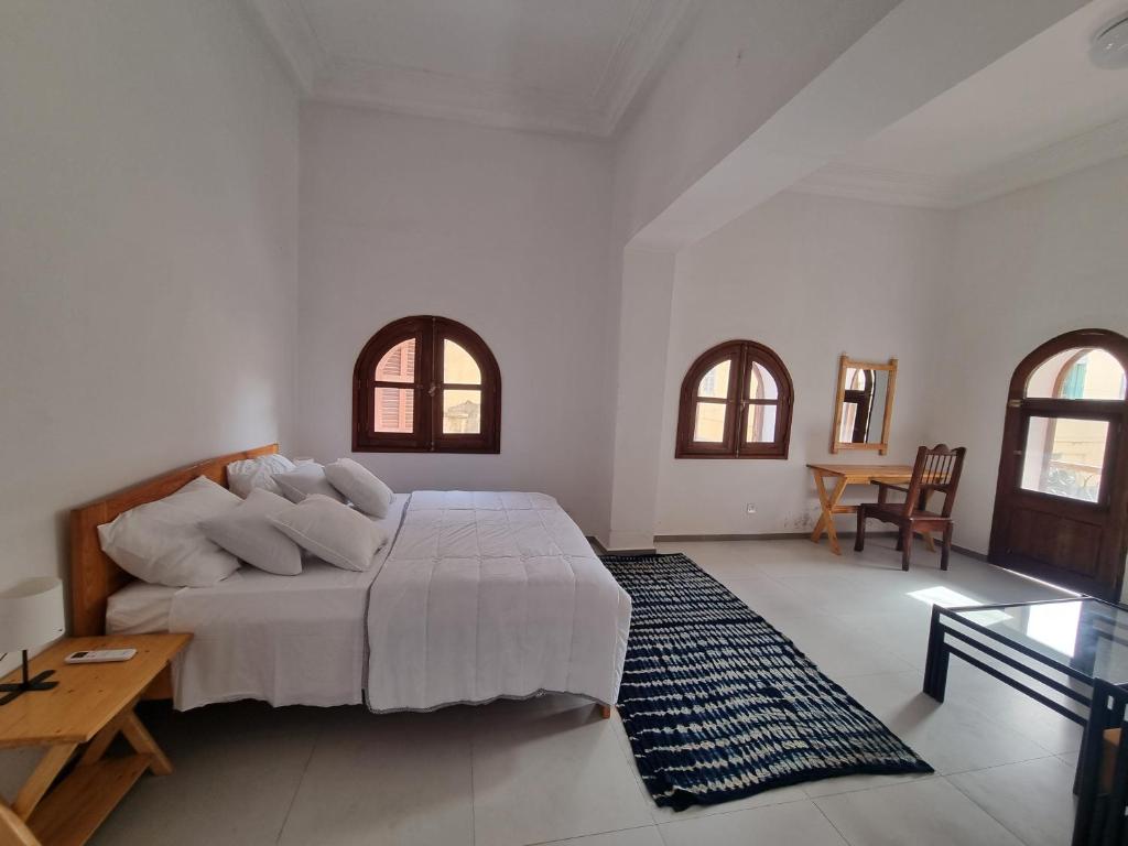 a bedroom with a bed and a table and windows at Maison Sakeena in Saint-Louis