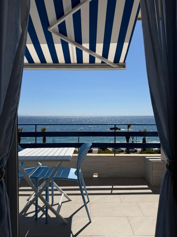 a table and a chair on a balcony with the ocean at vinaka in SantʼAlessio Siculo