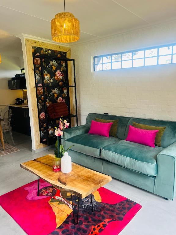 a living room with a green couch and a table at Origin Cottage in eMalahleni