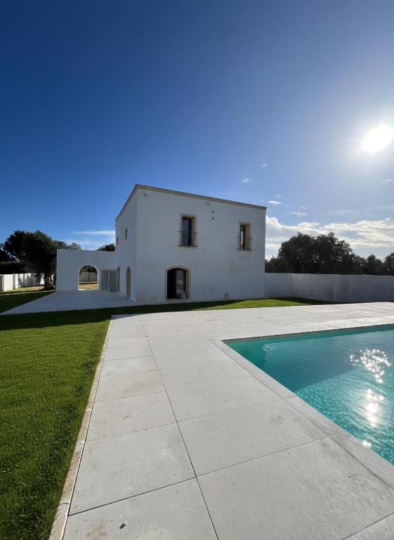 a white house with a swimming pool in front of it at Giù al Vigneto in Leporano