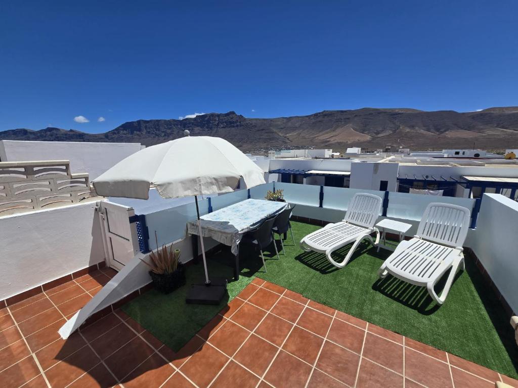 a patio with a table and chairs and an umbrella at Casa Naya in Famara
