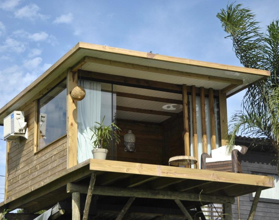 a tiny house with a large window on a deck at Suítes Âncora Praia do Rosa in Imbituba