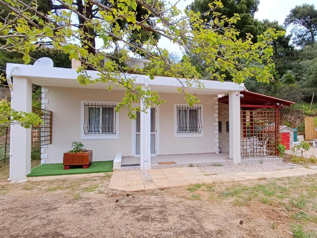 a small white house with a green lawn at Forest Retreat Near the Sea Kouvaras in Kouvarás