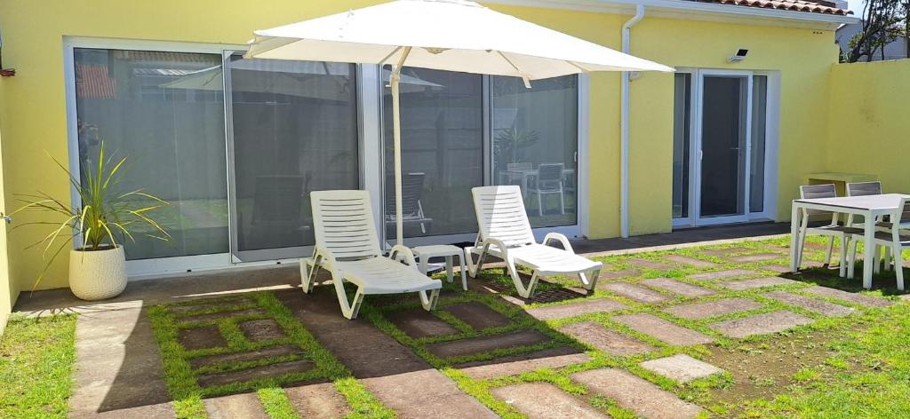 a patio with a table and chairs and an umbrella at Garden House 2 in São Vicente Ferreira