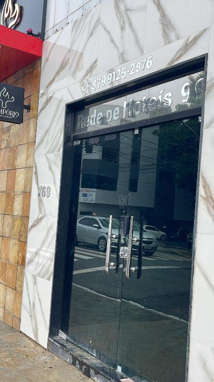 a door to a store with a reflection of a car at Rede de Hotel 99 in Garanhuns