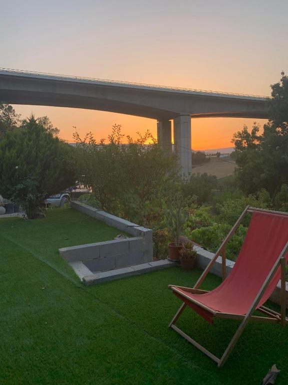 a red chair sitting on the grass with the sunset at Green cabin in our small garden in Arruda dos Vinhos
