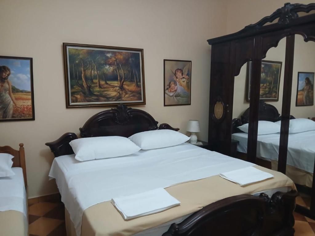 a bedroom with two beds and paintings on the wall at Roland Palaj House in Shkodër