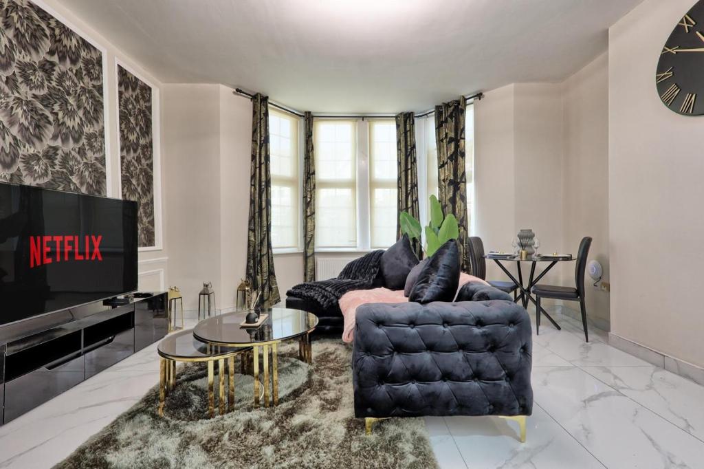a living room with a couch and a tv at Reeha's Hotel Apartments in Southend-on-Sea