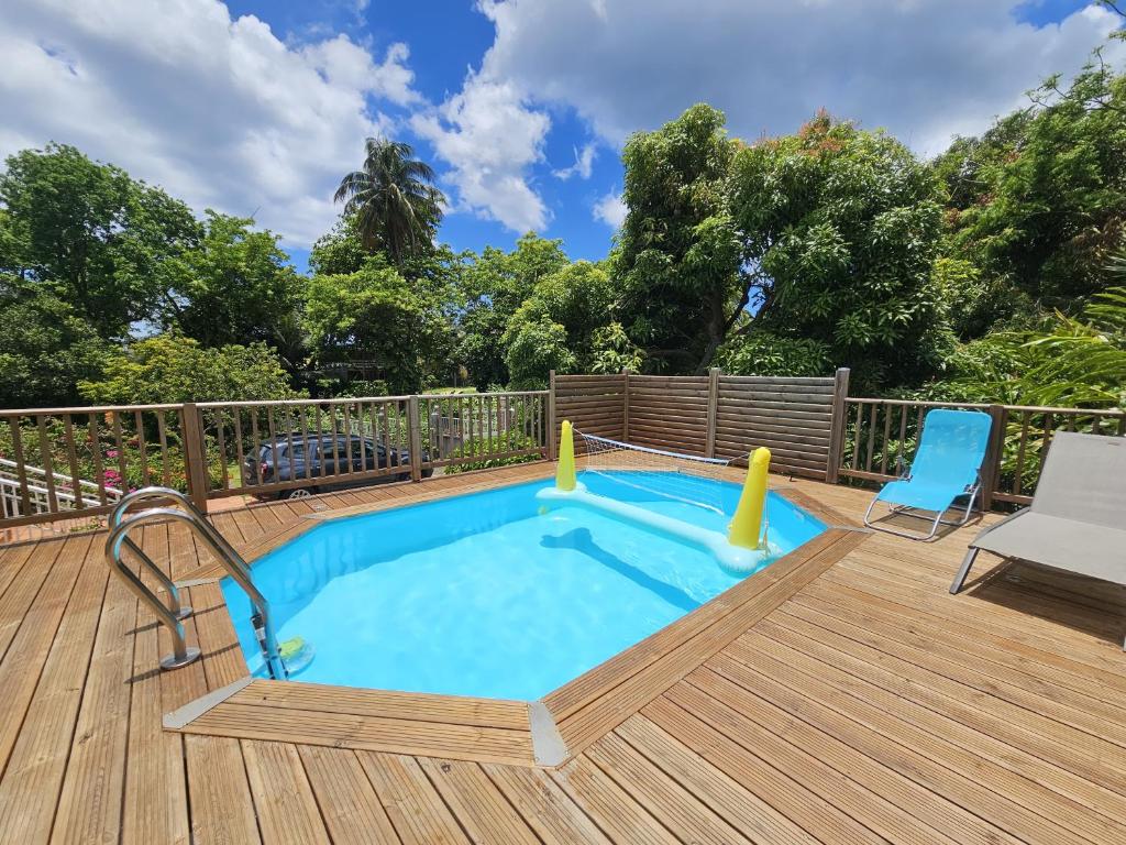 a lap pool on a deck with a chair and a blue chair at Villa IXORA- piscine privée, vue montagne, calme absolu proche plages in Trois-Rivières