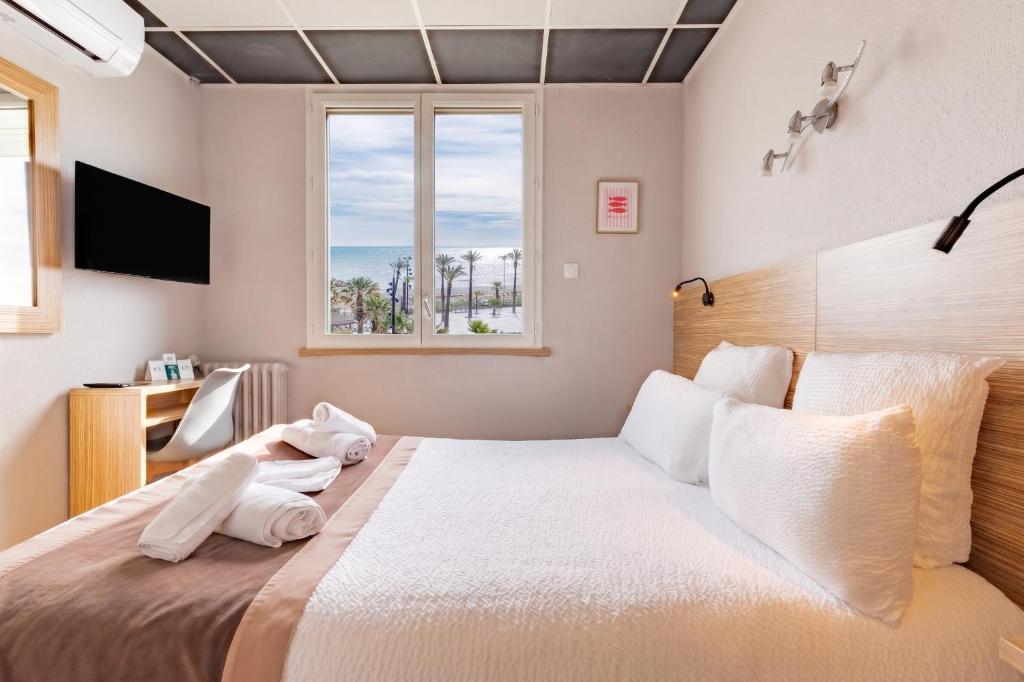 a bedroom with a bed with white sheets and a window at Logis Mar I Sol - Hôtel Restaurant en bord de Mer in Saint-Cyprien