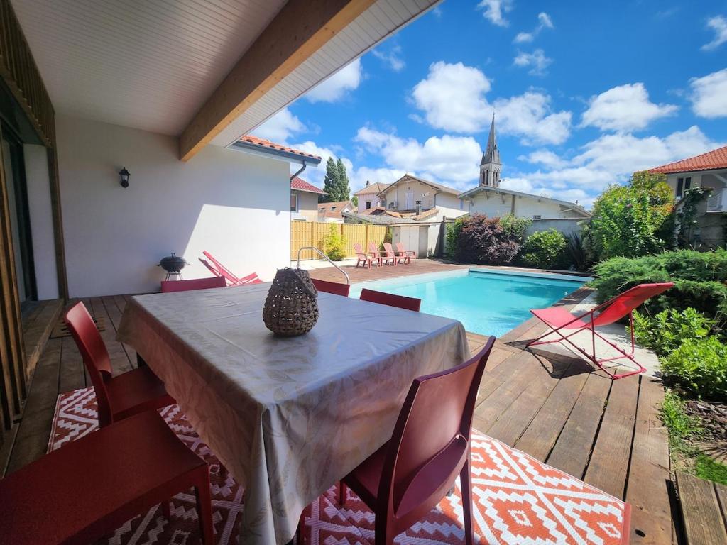 a patio with a table and chairs and a swimming pool at Maison centre-ville , pisicne in Mimizan