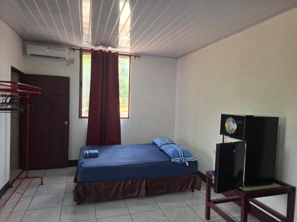 a bedroom with a bed and a tv and a window at Mandy's Villa in Bluefields