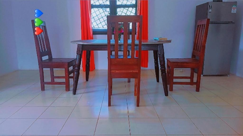 a dining room table with two chairs and a refrigerator at Honeymoon villah in Diani Beach