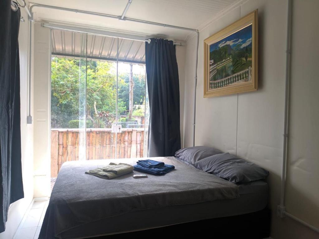 a bed in a room with a window and a bedvisor at Condomínio Containers está localizado a 900m do centro de Morretes, local calmo e em meio a mata Atlântica in Morretes