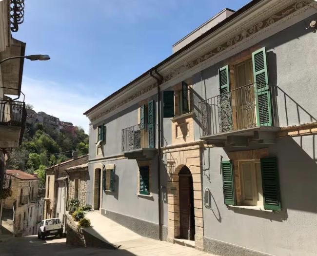 a white building with green shutters on a street at Casa Sirolli in Archi
