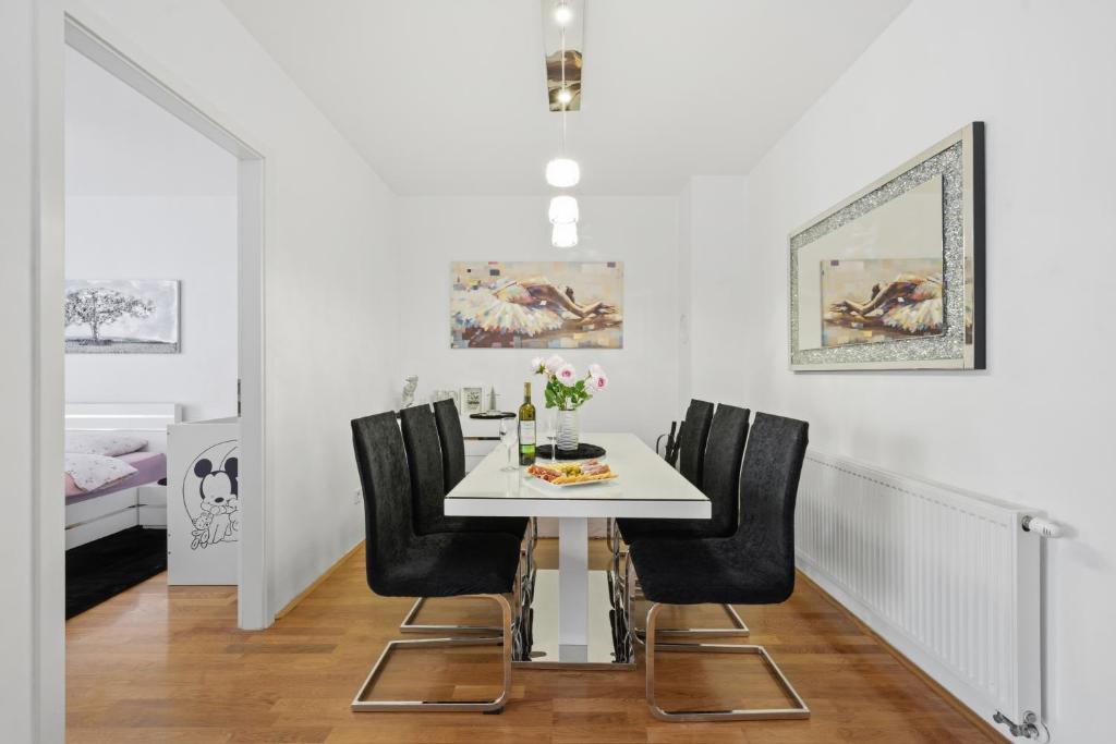 a dining room with a white table and black chairs at Apartman Tonka in Šibenik