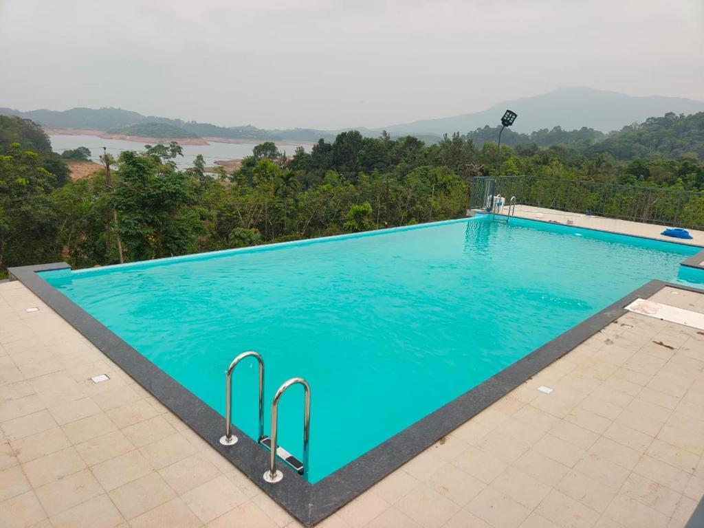 a large blue swimming pool with a mountain in the background at Nirvanica Retreat Wayanad in Padinjarathara