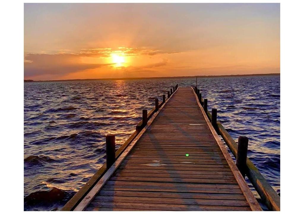 a wooden pier in the water with a sunset at Birken Loft am Meer in Neustadt am Rübenberge